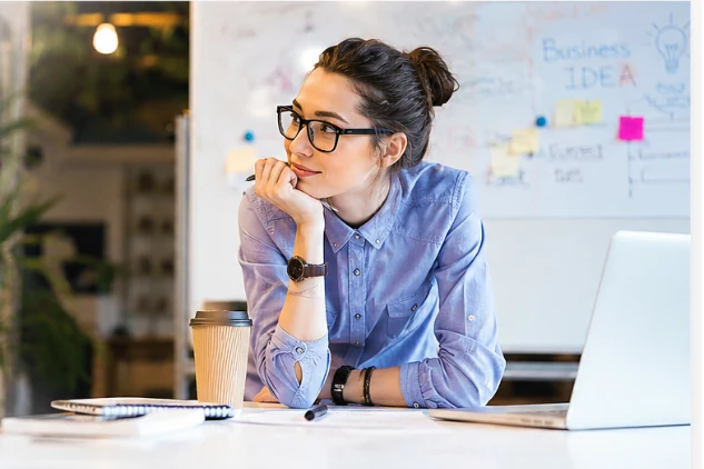 Woman reviewing business ideas at a desk with a laptop and planning board